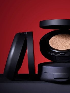 Image publicitaire du produit L'Oréal Paris Le Duo Serum. Le flacon luxueux, aux accents dorés et au corps transparent révélant deux formules distinctes (une claire et une ambrée), est présenté en diagonale. L'arrière-plan se compose de vagues onctueuses et satinées de textures blanches et dorées qui s'entrelacent, symbolisant la puissance et la richesse du mélange de sérums.