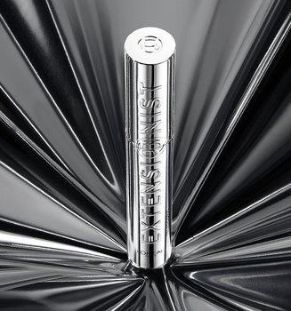 Un seul tube de mascara L'Oréal argenté posé verticalement au centre d'un fond argenté réfléchissant spectaculaire avec un motif lumineux radial.