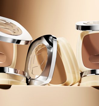 Quatre poudriers carrés de fond de teint L'Oréal dans diverses teintes allant du beige clair au bronzé foncé, présentés sur un fond marron doré chaud.