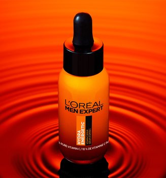 Orange bottle of L'Oréal Men Expert Hydratatic Serum with a black dropper, on a reflective red surface with ripples.