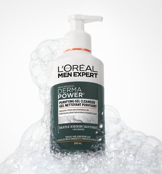 White bottle of L'Oréal Men Expert Derma Power Purifying Gel Cleanser with a pump, surrounded by white soap bubbles on a grey background.