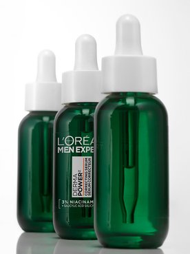 Trois flacons verts de sérum correcteur L'Oréal Men Expert Power Age avec pipettes, alignés sur un fond blanc.