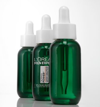 Trois flacons verts de sérum correcteur L'Oréal Men Expert Power Age avec pipettes, alignés sur un fond blanc.