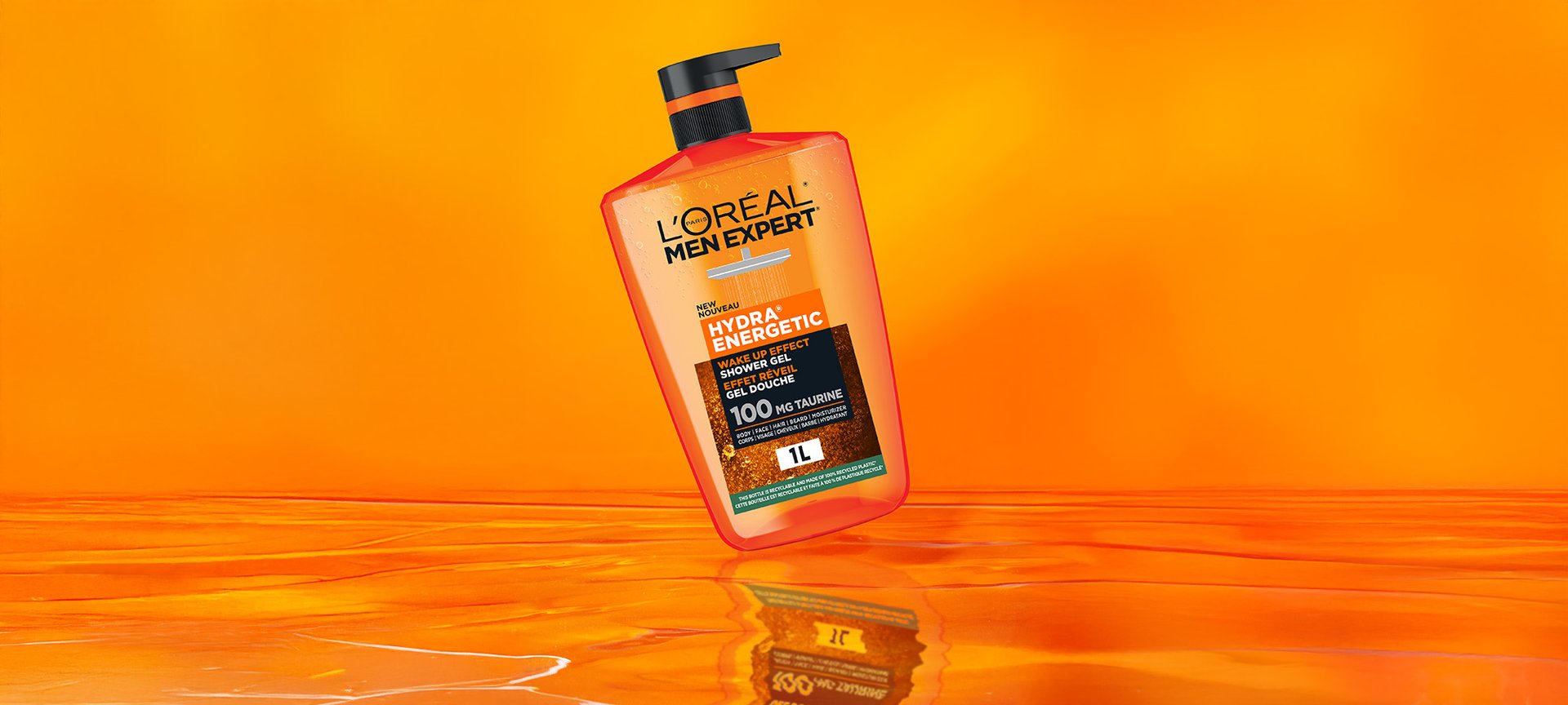 Orange bottle of L'Oréal Men Expert Hydra Energetic Shower Gel with a black pump, floating on a bright orange background with a reflective surface.
