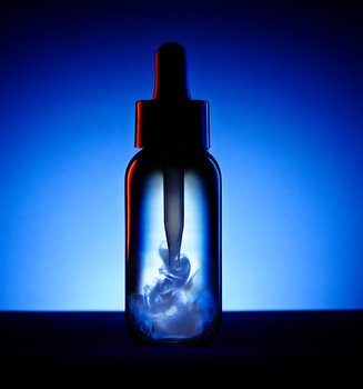 Dark bottle with a dropper containing white liquid swirling inside, set against a deep blue and black background.