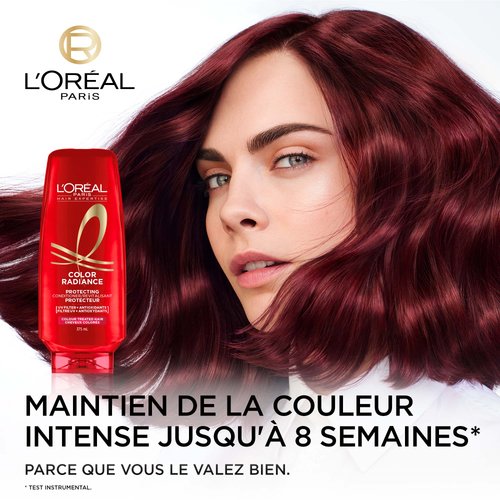 Cara Devigne avec les cheveux rouge et une bouteille de revitalisant Color Radiance
