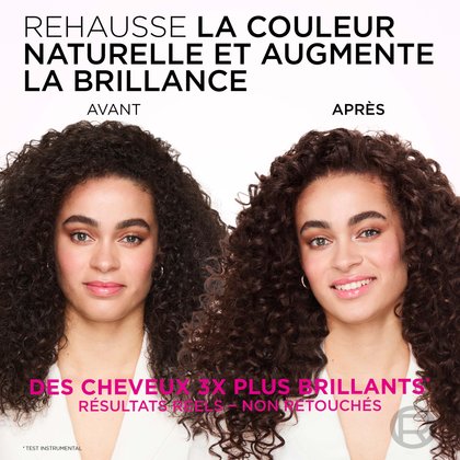 Une image divisée montrant une femme aux cheveux bouclés et volumineux avant et après un traitement visant à rehausser la couleur naturelle et à augmenter la brillance. À gauche, étiqueté "BEFORE" (AVANT), ses cheveux sont châtain foncé, apparaissant un peu ternes, et son expression est neutre. À droite, étiqueté "AFTER" (APRÈS), ses cheveux sont d'un châtain foncé plus riche et plus profond avec un fini brillant notable, et ses boucles semblent plus vibrantes et définies. Elle sourit largement. Le texte en haut indique : "ENHANCE NATURAL COLOUR & BOOST SHINE" (AMÉLIORER LA COULEUR NATURELLE ET BOOSTER L'ÉCLAT). Sous les images, il est écrit : "3X GLOSSIER HAIR*" (CHEVEUX 3X PLUS BRILLANTS*) et "REAL RESULTS - NOT RETOUCHED" (RÉSULTATS RÉELS - NON RETOUCHÉS), avec un astérisque précisant "*INSTRUMENTAL TEST" (TEST INSTRUMENTAL).