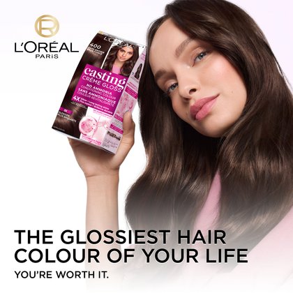 A woman with long, glossy dark brown hair smiles slightly, looking upwards. She holds a box of L'Oréal Casting Crème Gloss hair dye in shade 400 Dark Brown, which is prominently displayed with text highlighting "NO AMMONIA," "CONDITIONING COLOUR," and "silky + Long-lasting shine." The L'Oréal Paris logo is visible in the upper left corner. Below the woman, large text reads The glossiest hair color ever seen and you're worth it.