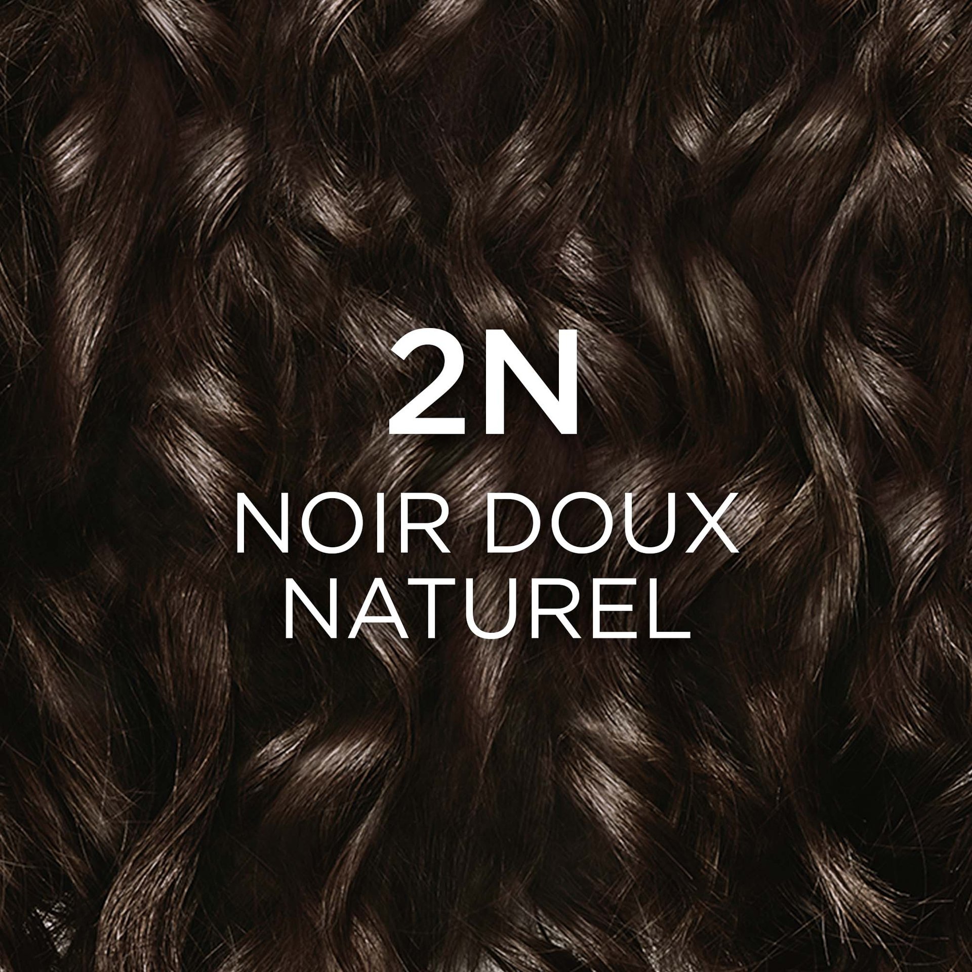 Gros plan sur une mèche de cheveux ondulés, très foncés, de couleur noir doux naturel, avec le texte blanc "2N NOIR DOUX NATUREL" superposé.