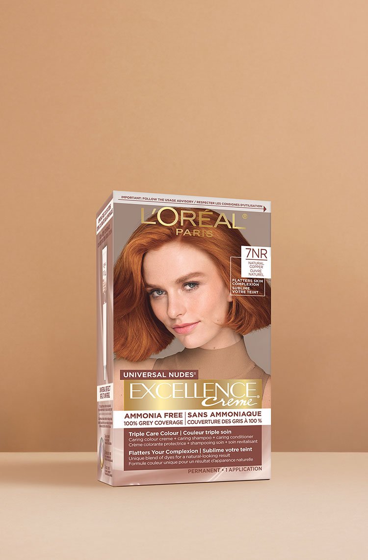 Boîte de coloration capillaire L'Oréal Excellence Crème Universal Nudes 7NR châtain clair cuivré, présentant une femme rousse souriante aux cheveux mi-longs, brillants et cuivrés.