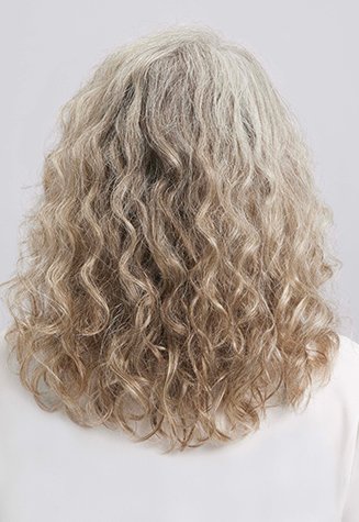 Back view of a person with long, curly hair in natural grey and silver tones, wearing a white top against a neutral light grey background.
