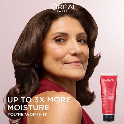 L'Oréal Paris advertisement featuring a smiling woman with voluminous, glossy brown wavy hair wearing a red top, alongside the Excellence Crème Ultimate Conditioner tube. Text: Up to 3X More Moisture. You're Worth It.