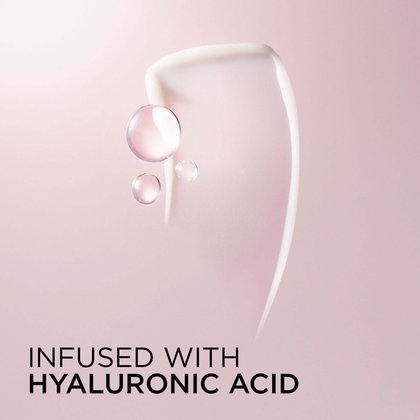 Artistic close-up of a white conditioner cream swirl with translucent pink hyaluronic acid droplet spheres on a blush pink background. Text: Infused with Hyaluronic Acid.