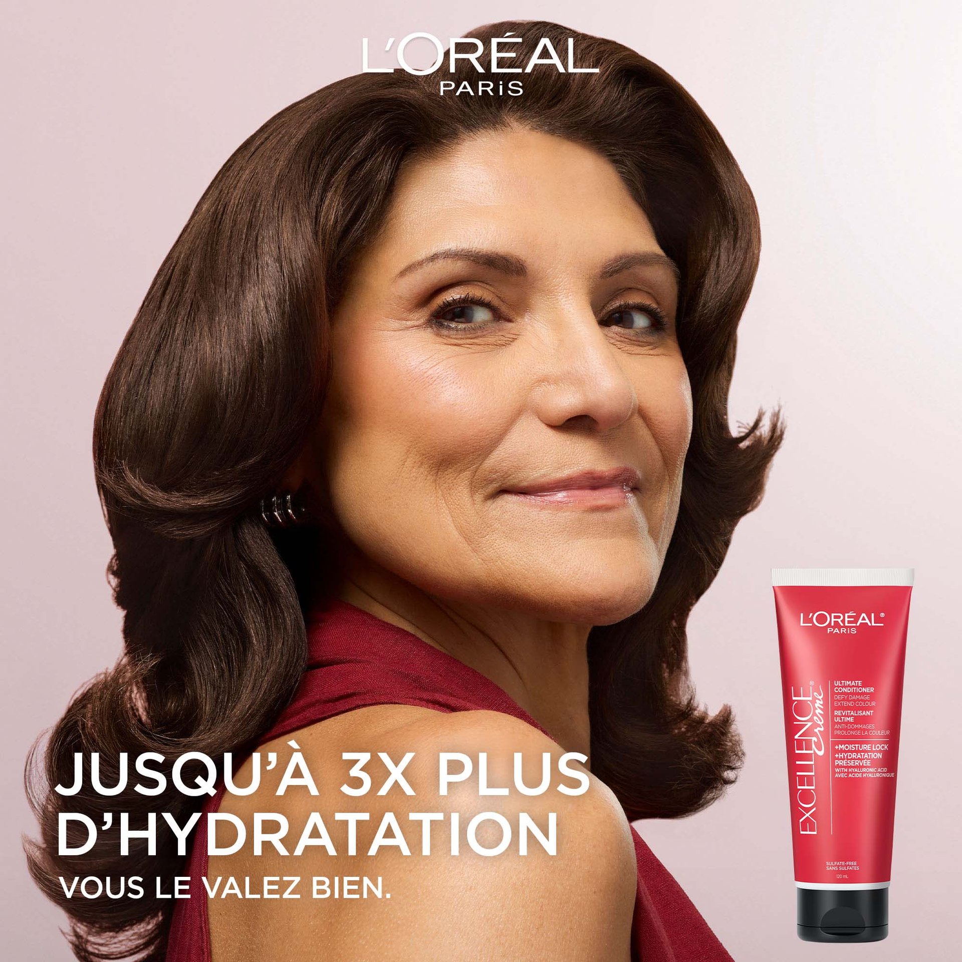 Publicité L'Oréal Paris mettant en vedette une femme souriante aux cheveux bruns ondulés, volumineux et brillants, portant un haut rouge, à côté du revitalisant ultime Excellence Crème. Texte : Jusqu'à 3X plus d'hydratation. Parce que vous le valez bien.