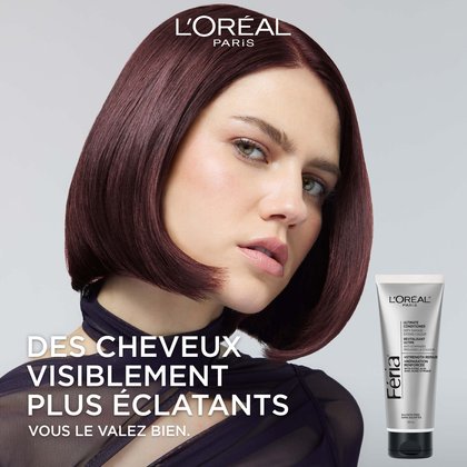 Image de campagne L'Oréal Paris mettant en scène un mannequin aux cheveux bordeaux-rouge profonds et brillants coiffés en carré plongeant, regardant directement l'objectif. Le texte indique : « Des cheveux visiblement plus éclatants – Parce que vous le valez bien. » Le tube argenté du Revitalisant Ultime Féria est visible en bas à droite. Logo L'Oréal Paris en haut de l'image.