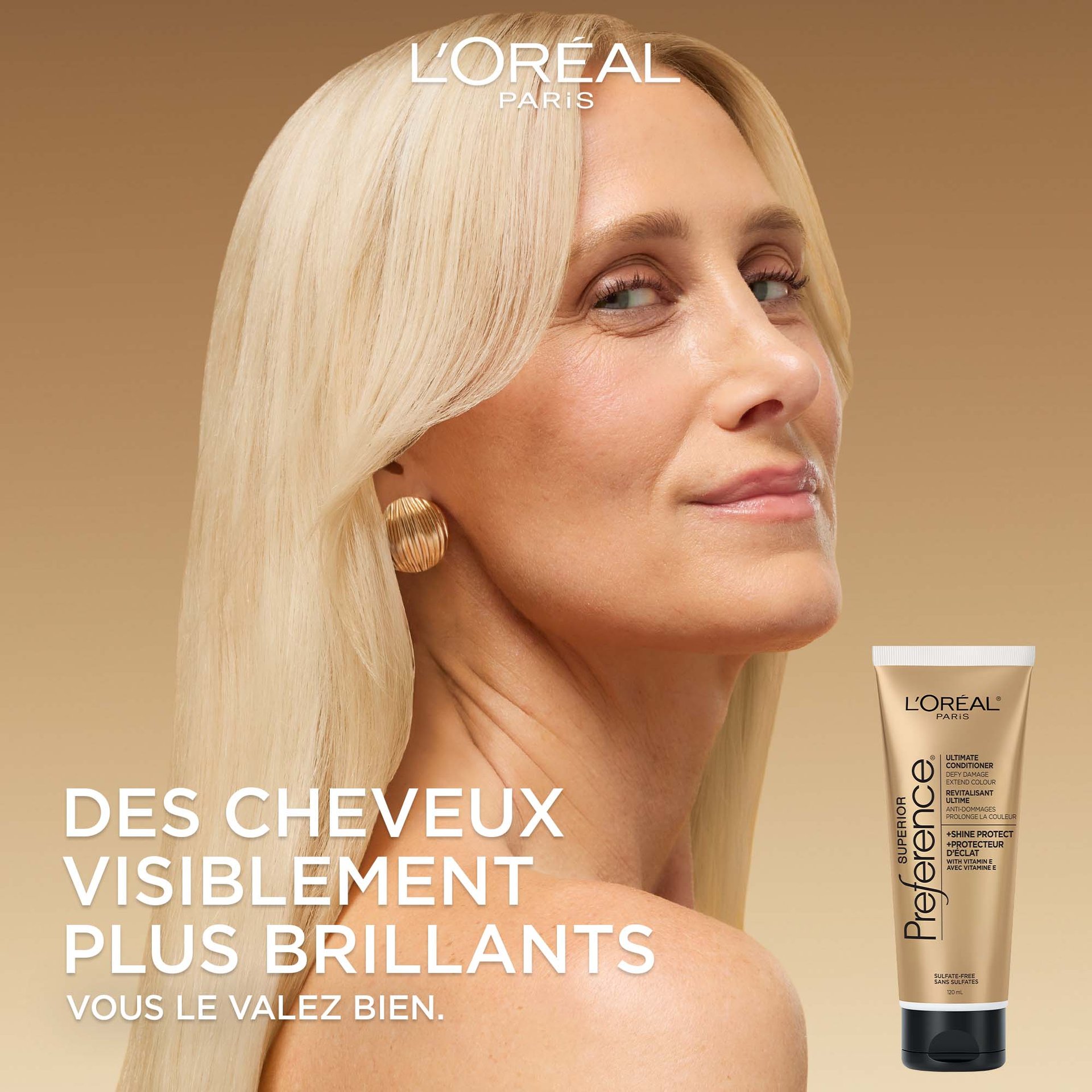 Une femme aux longs cheveux blonds lisses regarde par-dessus son épaule avec un léger sourire. Le fond est un dégradé doré doux. Le grand texte blanc à gauche dit : « Cheveux visiblement plus brillants. Parce que vous le valez bien. » Une image du tube de revitalisant se trouve dans le coin inférieur droit.