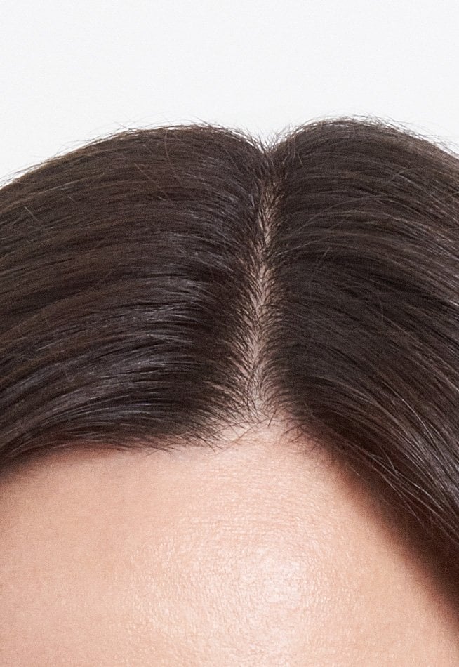 Close-up of the same hair after applying a concealer product; the grey roots are completely covered for a uniform and natural result.