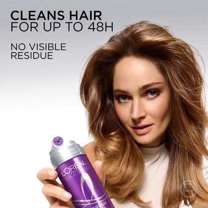 A smiling woman with voluminous brunette hair holding the purple dry shampoo spray. Text reads: 'Cleans hair for up to 48H. No visible residue.'