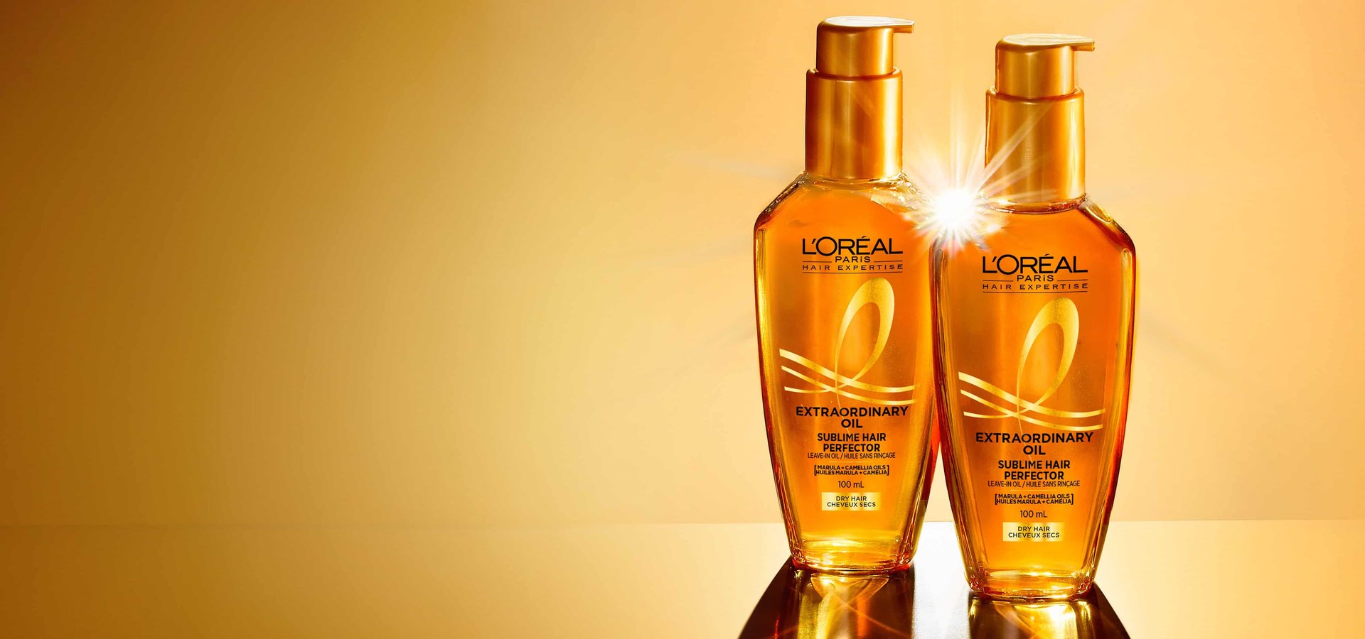 Two bottles of L'Oréal Paris Hair Expertise Extraordinary Oil Sublime Hair Perfector, with one showing a glowing highlight, on a golden background
