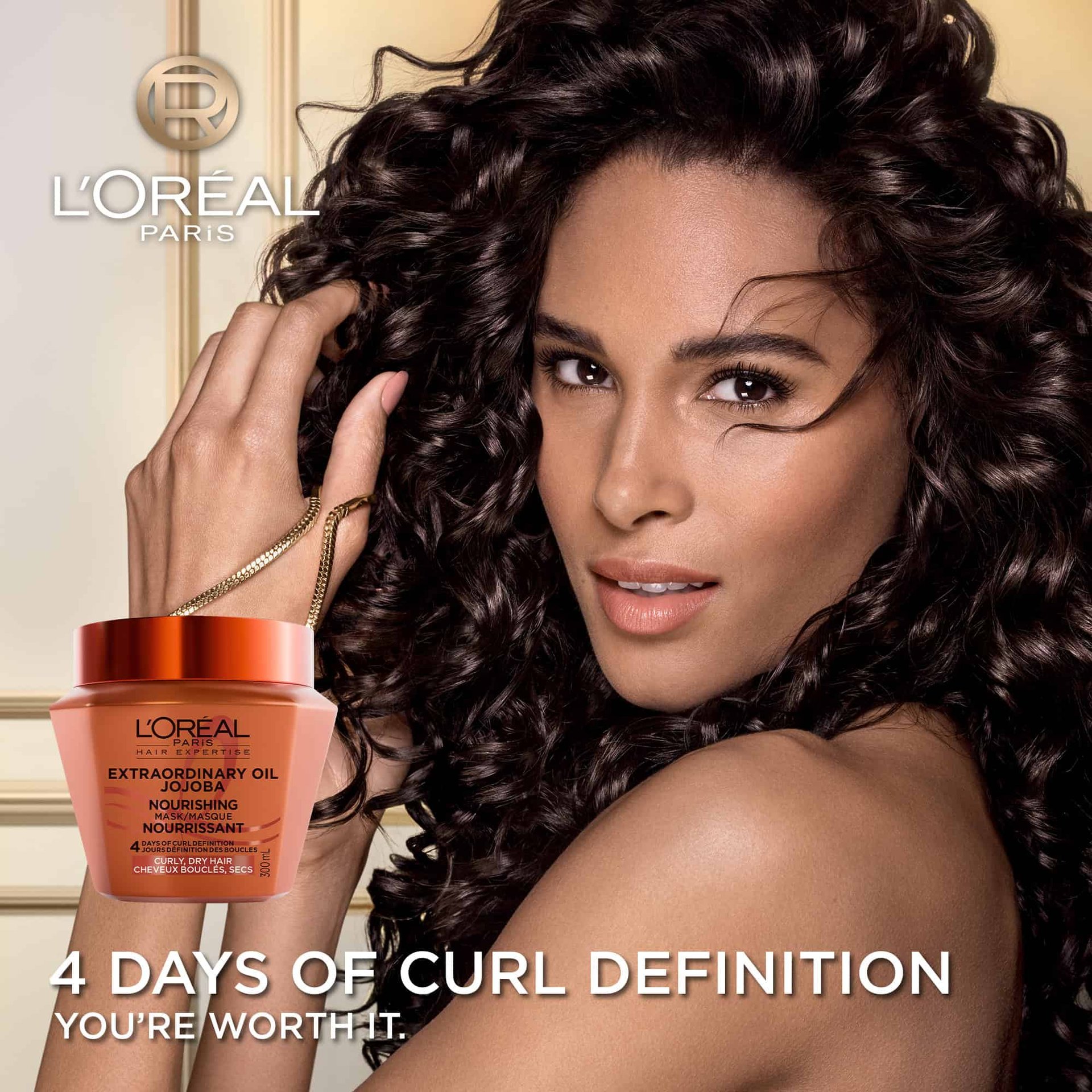 A woman with voluminous, shiny dark curly hair looking at the camera. In the bottom left, the L'Oréal Paris Jojoba Nourishing Mask jar is displayed with the text "4 Days of Curl Definition".