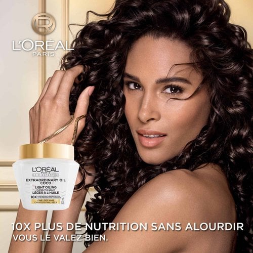 Une femme aux cheveux bouclés foncés, volumineux et brillants regardant l'objectif. En bas à gauche, le pot de masque à l'huile de coco s'affiche avec le texte « Nutrition 10x plus légère ».