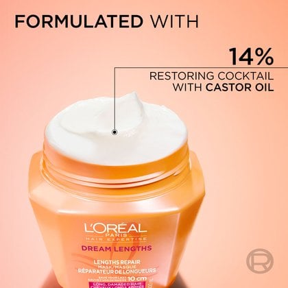 Close-up of the open orange jar of L'Oréal Paris Dream Lengths hair mask revealing smooth white cream inside. Text reads: "Formulated with 14% restoring cocktail with castor oil".