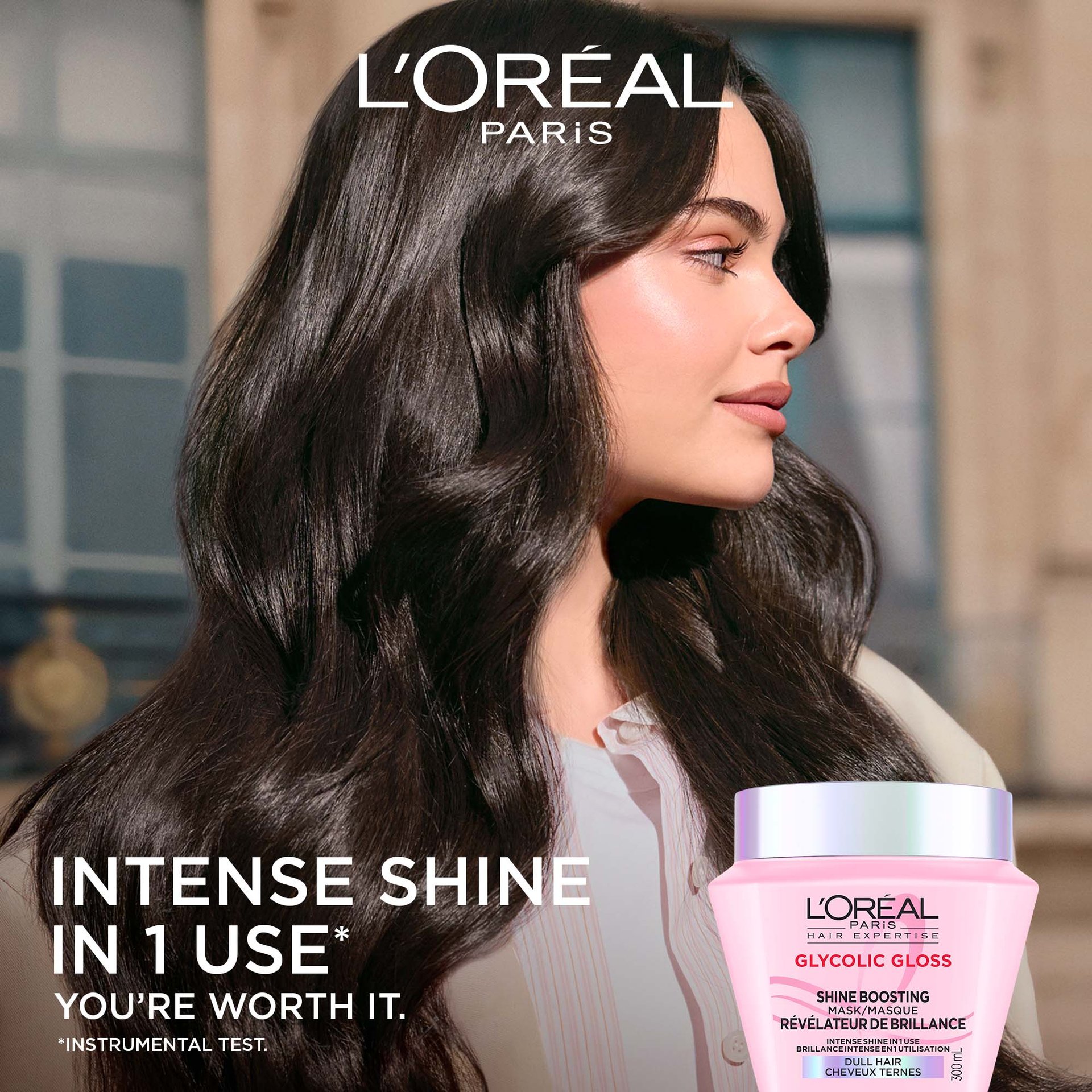 A side-profile view of a woman with long, smooth, and extremely shiny dark hair. To her left, the text reads "Intense shine in 1 use", with the pink hair mask jar in the bottom corner.