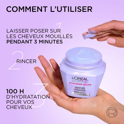 Des mains tenant le pot de masque violet et prélevant de la crème blanche. À gauche, les étapes d'utilisation indiquent : « Mode d'emploi : Appliquer sur cheveux mouillés pendant 2-3 minutes, rincer, 100 h d'hydratation pour vos cheveux ».