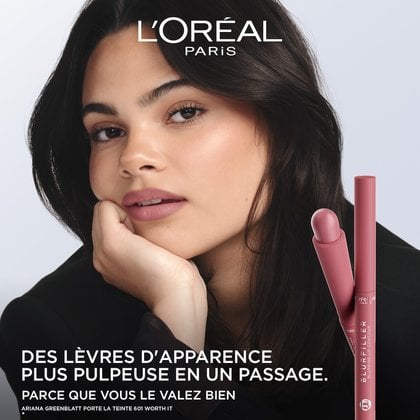 Une publicité L'Oréal mettant en scène l'actrice Ariana Greenblatt, avec une peau douce et lumineuse et portant un rouge à lèvres rose nude. Ses cheveux foncés encadrent son visage, et elle pose son menton sur sa main, regardant directement le spectateur. À droite, deux crayons L'Oréal Blurfiller Blurring Lip Contour d'une teinte rose-rosé sont présentés verticalement. Le texte de l'annonce indique 'DES LÈVRES PLUS PULPEUSES EN 1 SEUL PASSAGE. VOUS LE VALEZ BIEN.' et 'ARIANA GREENBLATT PORTE LA TEINTE #601 WORTH IT