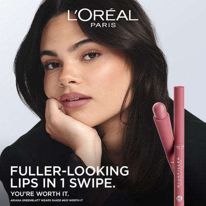 A L'Oréal advertisement featuring actress Ariana Greenblatt with soft, glowing skin and wearing a nude-pink lip color. Her dark hair frames her face, and she rests her chin on her hand, looking directly at the viewer. To the right, two L'Oréal Blurfiller Blurring Lip Contour pencils in a rosy-pink shade are shown vertically. The ad text reads 'FULLER-LOOKING LIPS IN 1 SWIPE. YOU'RE WORTH IT.' and 'ARIANA GREENBLATT WEARS SHADE #601 WORTH IT
