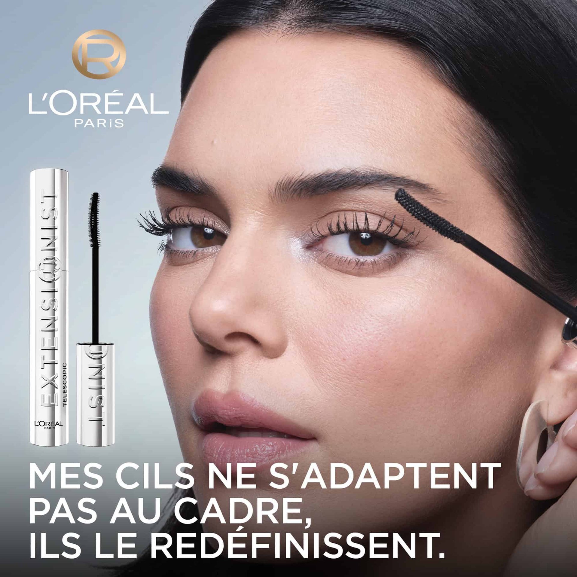  Kendall Jenner, les cils sublimés par le mascara, tient la brosse du mascara L'Oréal "Telescopic Extensionist" près de son œil. Le logo L'Oréal Paris est visible et le texte dit : "MES CILS NE S'ADAPTENT PAS AU CADRE, ILS LE REDÉFINISSENT.".