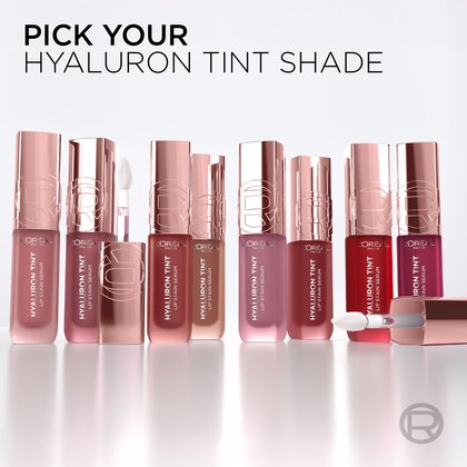 A row of nine L'Oréal Paris Hyaluron Tint product bottles, each representing a different shade, lined up on a white reflective surface, inviting the user to pick their color. Text prompts: 'PICK YOUR HYALURON TINT SHADE