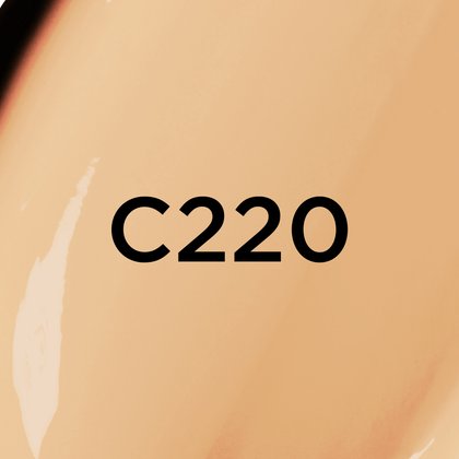 Un gros plan d'un fond de teint ou d'une texture crémeuse de couleur beige moyen à chaud, avec le texte noir en gras 'C220' centré sur l'image, indiquant probablement une teinte de produit