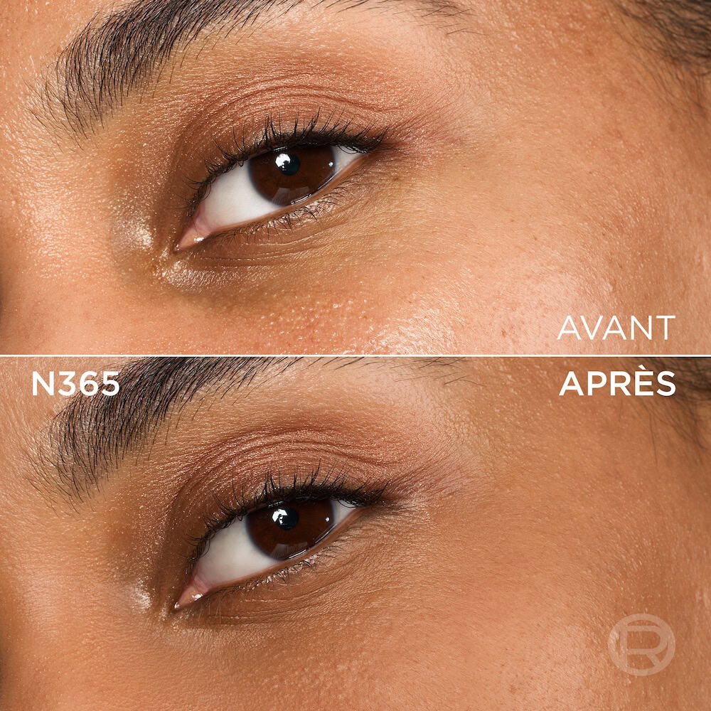 Image divisée montrant un comparatif avant et après de la zone sous l'œil et de la joue d'une personne à la peau de couleur moyenne à foncée et aux yeux marron. La section supérieure, étiquetée 'BEFORE' (Avant), présente une peau avec une texture visible, des pores et une légère inégalité de teinte sous l'œil, ainsi qu'un maquillage léger des yeux avec un fard à paupières doré-brun. La section inférieure, étiquetée 'N365' et 'AFTER' (Après), montre la même zone du visage avec une peau visiblement plus unifiée, plus lisse et des imperfections atténuées, suite à l'application d'un produit cosmétique. Le maquillage des yeux reste visible. Un discret logo 'R' est également visible en bas à droite de la partie 'APRÈS'