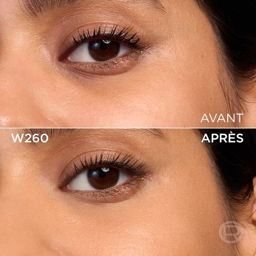 Image divisée montrant un comparatif avant et après de la zone sous l'œil et de la joue d'une personne à la peau de couleur moyenne et aux yeux marron. La section supérieure, étiquetée 'BEFORE' (Avant), présente une peau avec une texture visible, des pores et une légère décoloration sous l'œil, ainsi qu'un mascara appliqué sur les cils. La section inférieure, étiquetée 'W260' et 'AFTER' (Après), montre la même zone du visage avec une peau visiblement plus unifiée, plus lisse et des imperfections atténuées, suite à l'application d'un produit cosmétique. Le mascara reste visible. Un discret logo 'R' est également visible en bas à droite de la partie 'APRÈS'
