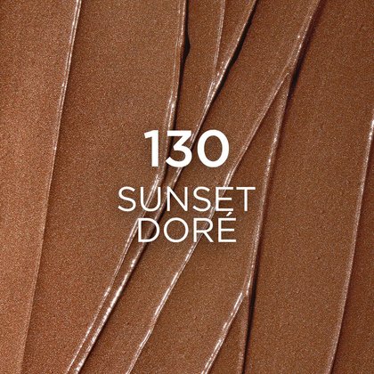 A close-up, textured swatch of makeup in shade '130 Sunset Doré', featuring a deep, shimmering golden-brown color with visible, lustrous streaks and a finely milled sparkle