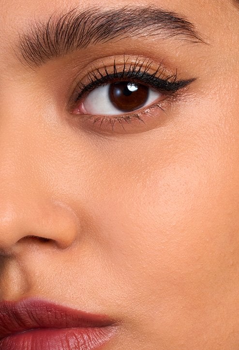 Close-up "After" shot of a model's face with a tan skin tone, highlighting the even texture and high-definition finish of the foundation.