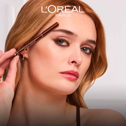 A model with elegant bronze eye makeup holding the Haute Couleur Kohl Eyeliner near her face to demonstrate its vibrant colour payoff.