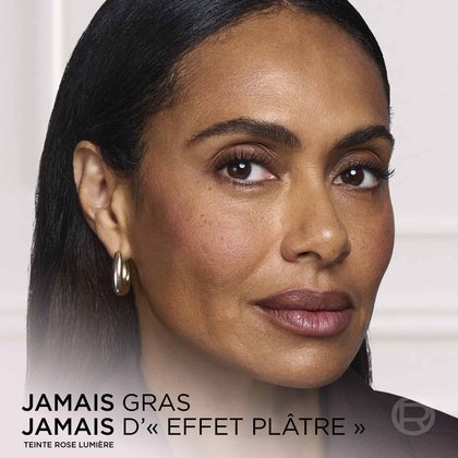 Portrait en gros plan d'une femme affichant un maquillage au fini lisse, impeccable et radieux, avec le texte superposé "NEVER GREASY NEVER CAKEY".