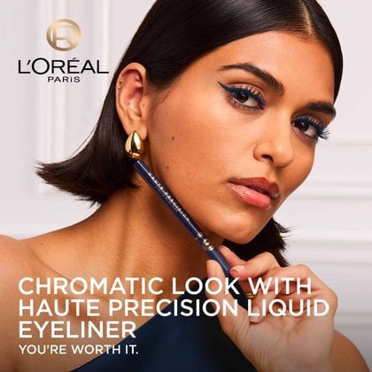 A stylish model with a bold, chromatic blue eyeliner and mascara look gazes towards the viewer, holding the dark blue L'Oréal Paris Haute Precision Liquid Eyeliner. She wears large gold earrings. The L'Oréal Paris logo is in the top left corner, and the text "CHROMATIC LOOK WITH HAUTE PRECISION LIQUID EYELINER YOU'RE WORTH IT