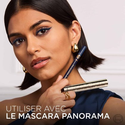 Une mannequin avec un eye-liner brun, tenant le L'Oréal Paris Haute Précision Liquid Eyeliner brun et un mascara doré Panorama. Le texte en bas dit : 'UTILISER AVEC LE MASCARA PANORAMA