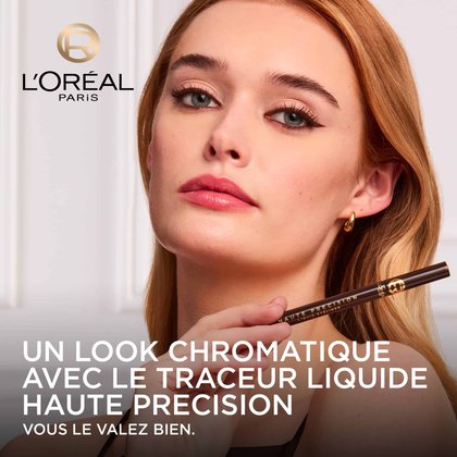 ne mannequin avec un regard souligné d'un eye-liner liquide brun intense, tenant le L'Oréal Paris Haute Précision Liquid Eyeliner brun. Le logo L'Oréal Paris est visible et le texte 'UN LOOK CHROMATIQUE AVEC LE TRACEUR LIQUIDE HAUTE PRÉCISION VOUS LE VALEZ BIEN.' est affiché
