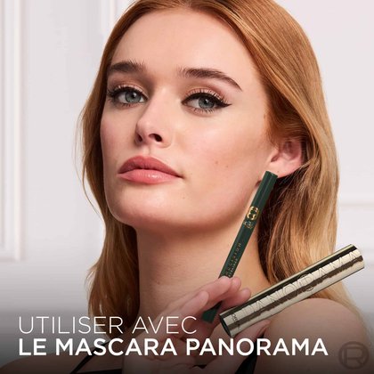 Une mannequin avec un eye-liner vert, tenant le L'Oréal Paris Haute Précision Liquid Eyeliner vert et un mascara doré Panorama. Le texte en bas dit : 'UTILISER AVEC LE MASCARA PANORAMA