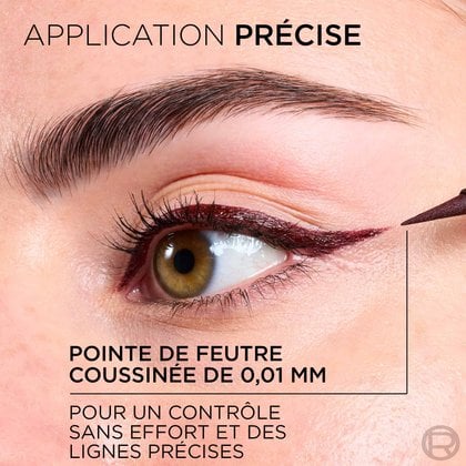 Gros plan sur un œil avec l'application précise d'un eye-liner liquide bordeaux. Le texte indique : 'APPLICATION PRÉCISE' et 'POINTE DE FEUTRE COUSSINÉE DE 0,01 MM POUR UN CONTRÔLE SANS EFFORT ET DES LIGNES PRÉCISES