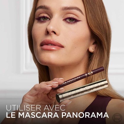 Une mannequin avec un eye-liner bordeaux, tenant le L'Oréal Paris Haute Précision Liquid Eyeliner bordeaux et un mascara doré Panorama. Le texte en bas dit : 'UTILISER AVEC LE MASCARA PANORAMA'