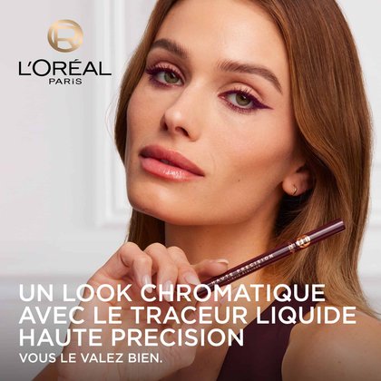 Une mannequin avec un regard souligné d'un eye-liner liquide bordeaux intense, tenant le L'Oréal Paris Haute Précision Liquid Eyeliner. Le logo L'Oréal Paris est visible et le texte 'UN LOOK CHROMATIQUE AVEC LE TRACEUR LIQUIDE HAUTE PRÉCISION VOUS LE VALEZ BIEN.' est affiché