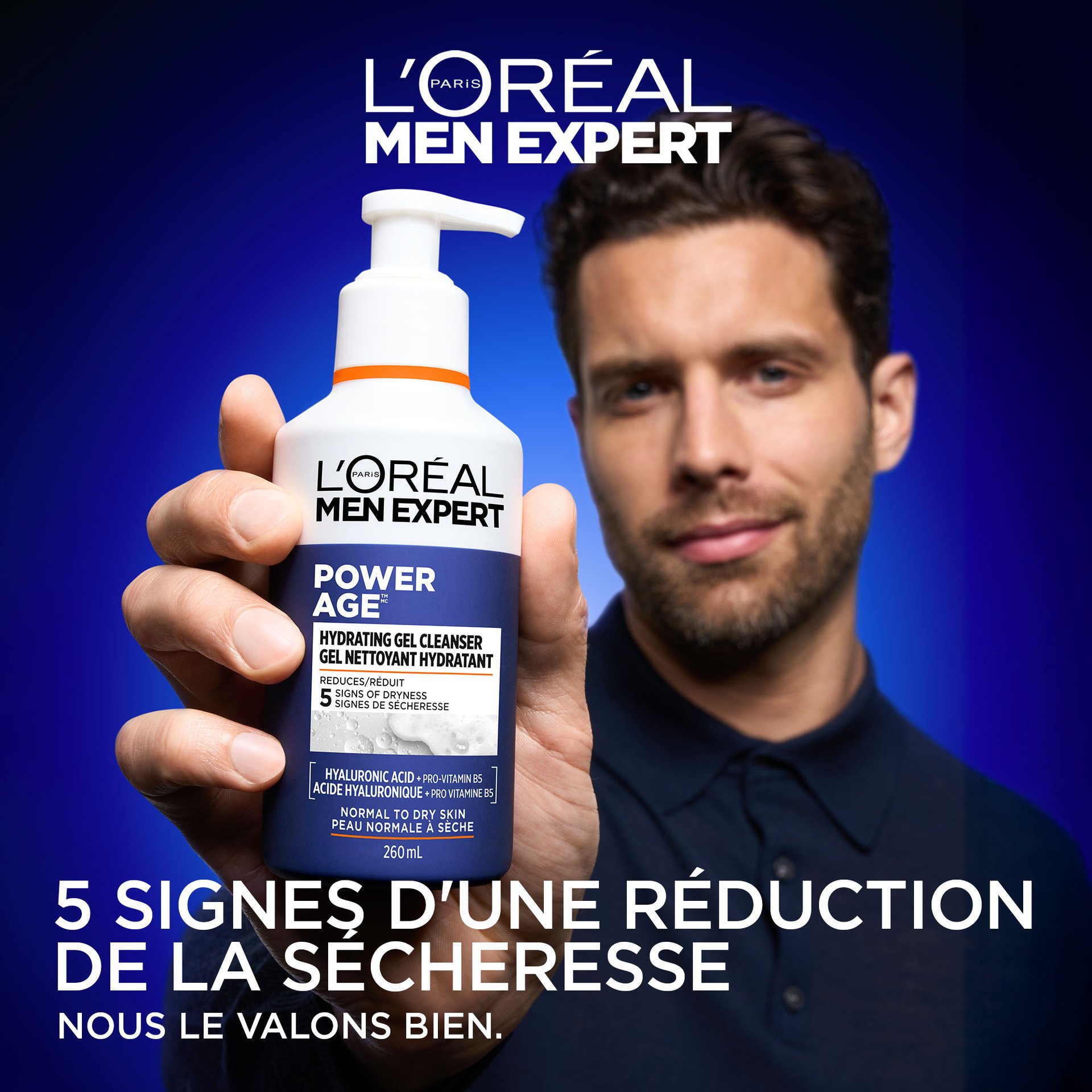 "n homme aux cheveux courts et foncés et portant une barbe tient le flacon de Gel Nettoyant Hydratant Power Age près de l'appareil photo. Le fond est d'un bleu dégradé éclatant. Un grand texte en bas indique « 5 SIGNES DE SÉCHERESSE RÉDUITS » avec le slogan de L'Oréal « PARCE QUE NOUS LE VALONS BIEN ». Image 3: Key Ingredients"