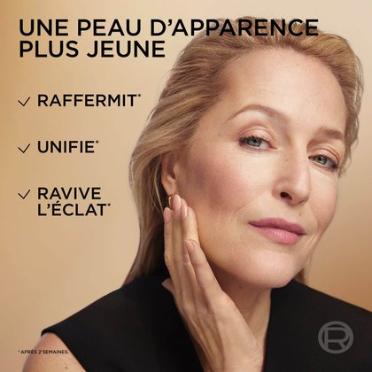 Un portrait en gros plan de l'actrice Gillian Anderson, mettant en valeur son teint éclatant et ferme. Le texte superposé souligne les avantages d'une "Peau d'apparence plus jeune", qui "Raffermit", "Unifie*" et "Booste l'éclat*" (*après 2 semaines).