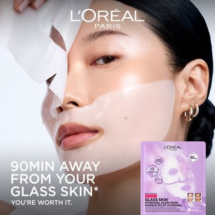 A portrait of an East Asian woman applying the translucent, jelly-like hydrogel sheet mask onto her skin. The text reads: "90 Min Away From Your Glass Skin".