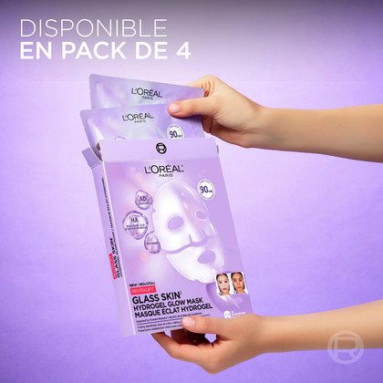 Gros plan sur des mains tenant et présentant le format pack de 4 des sachets de masques hydrogel L'Oréal Paris Revitalift Glass Skin sur un fond lavande.